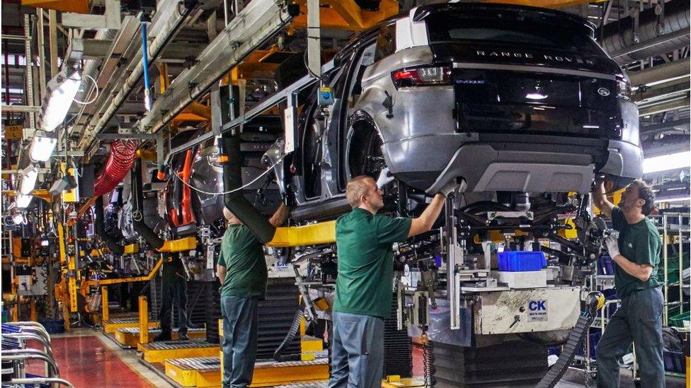 People installing engines in cars on a production line