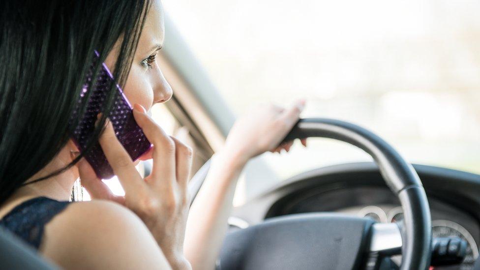 Woman driver on her mobile phone at the wheel