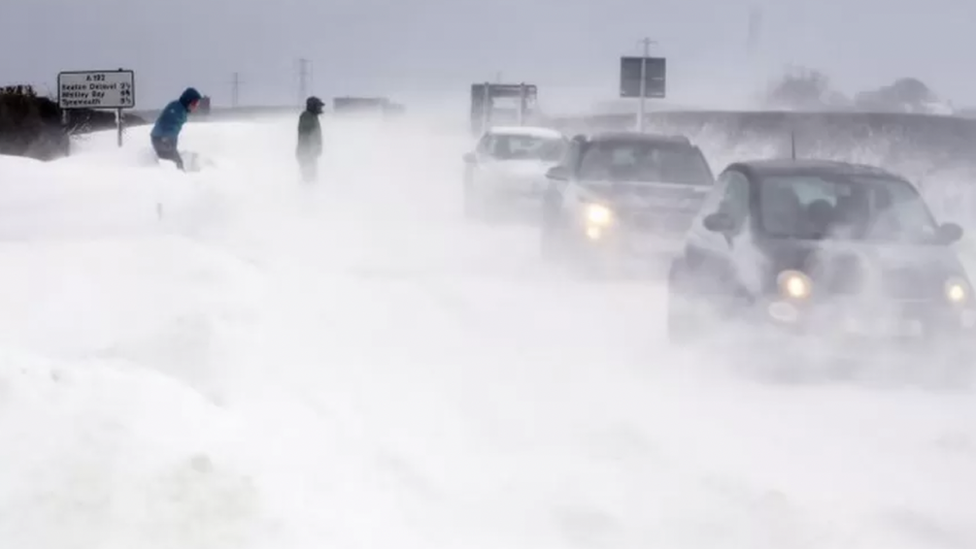 Cars travelling on a snow covered road with blizzards