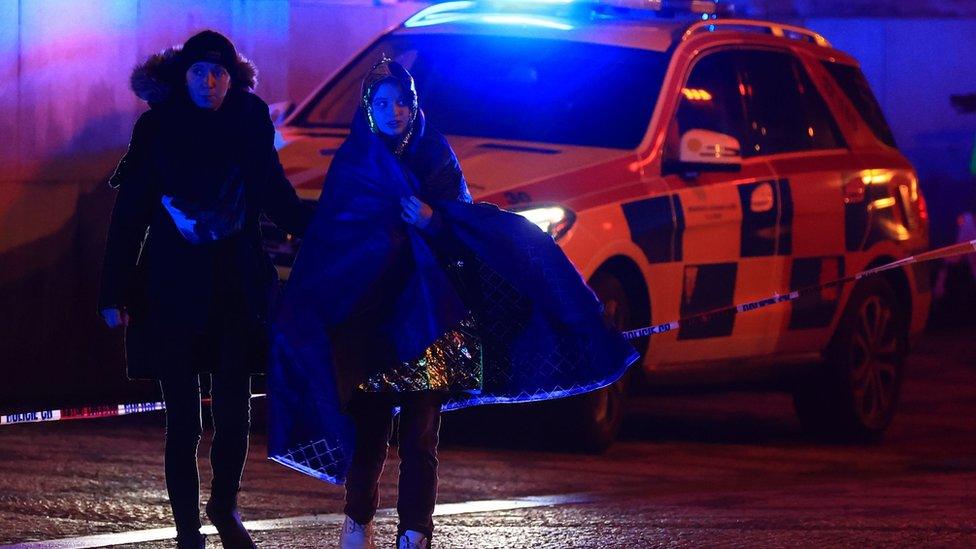 A person is escorted from the scene of a shooting at Charles University in central Prague, 21 December 2023.