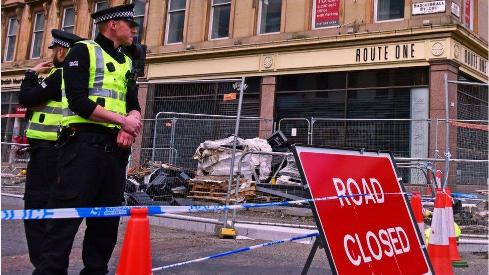 Police officers stand at road closed sign near remains of Glasgow School of Art