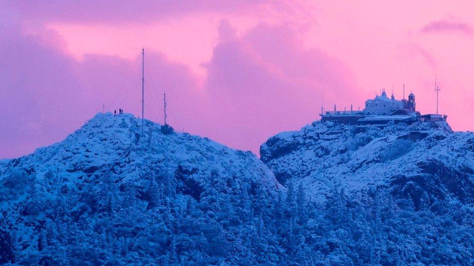 This picture shows the hill of Lycabettus with people braving rare heavy snowfall in the city of Athens