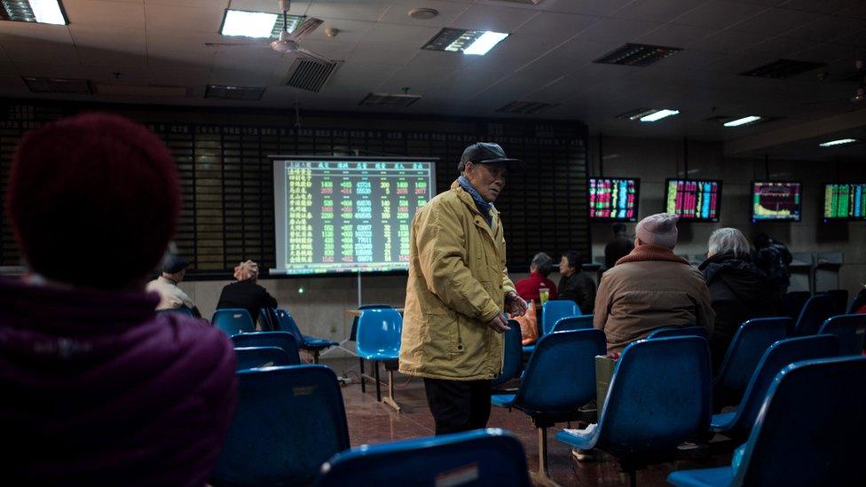 Investors monitor screens showing stock market movements at a brokerage house in Shanghai