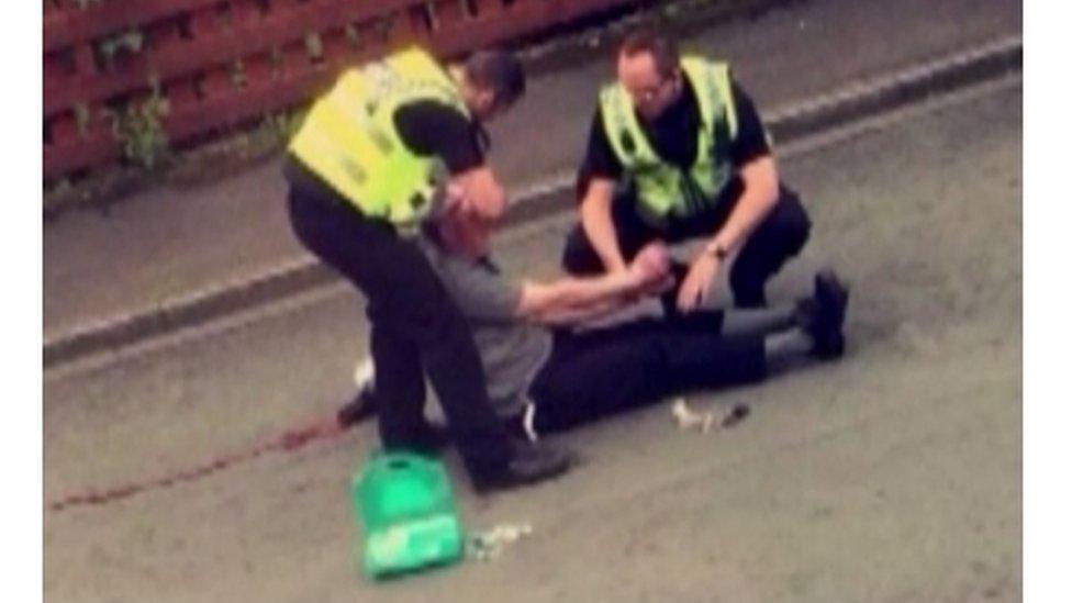 Police officers standing over Thomas Mair during his arrest