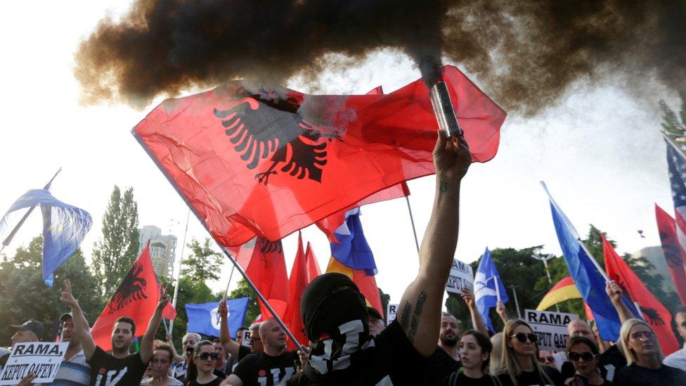 An opposition supporter carrying a smoke can attends an anti-government protest