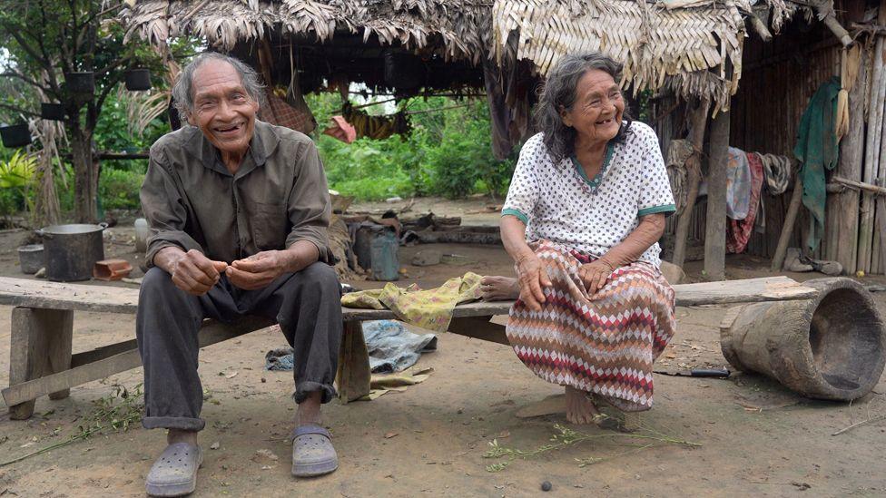 Hilda and Pablo sitting on a bench outside their home