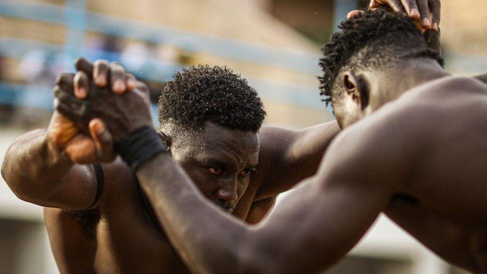 Two Senegalese men clasp hands as they wrestle in the capital Dakar on 9 June.