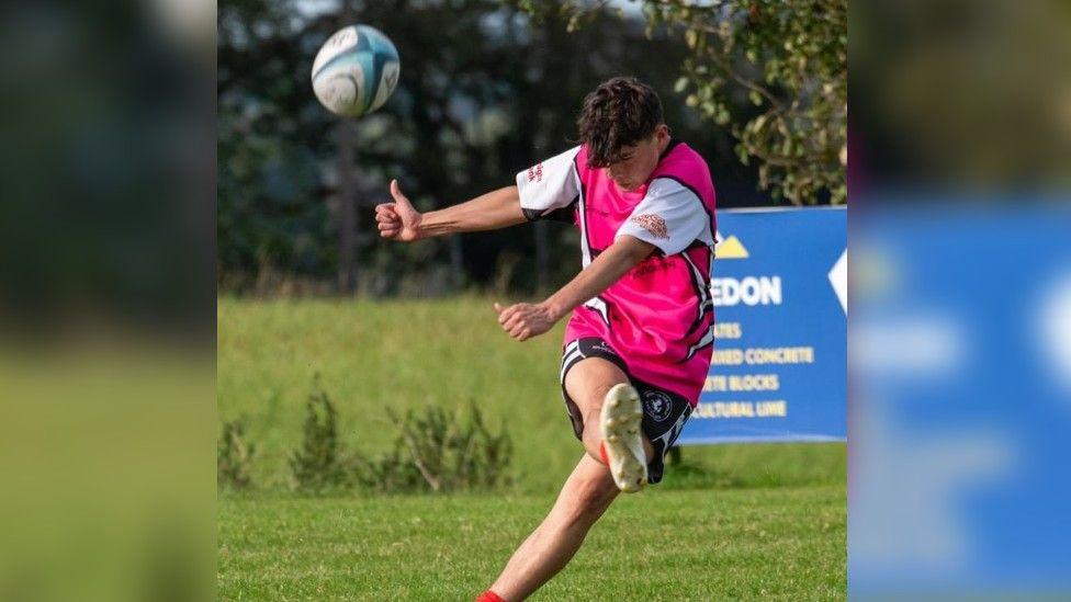 Harvey kicking a rugby ball during a match