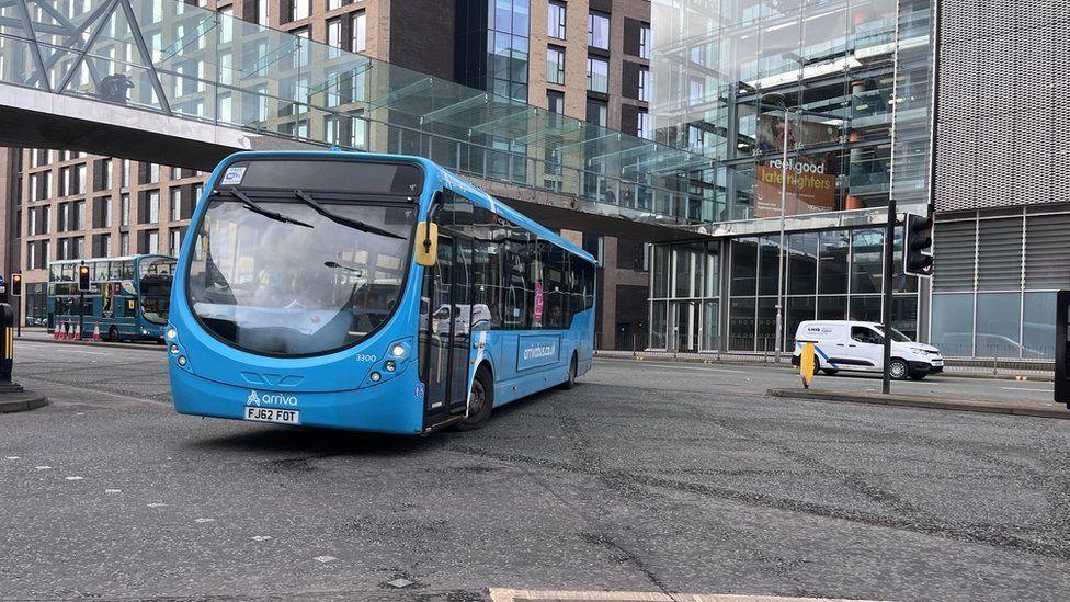 A blue bus driving across a junction.