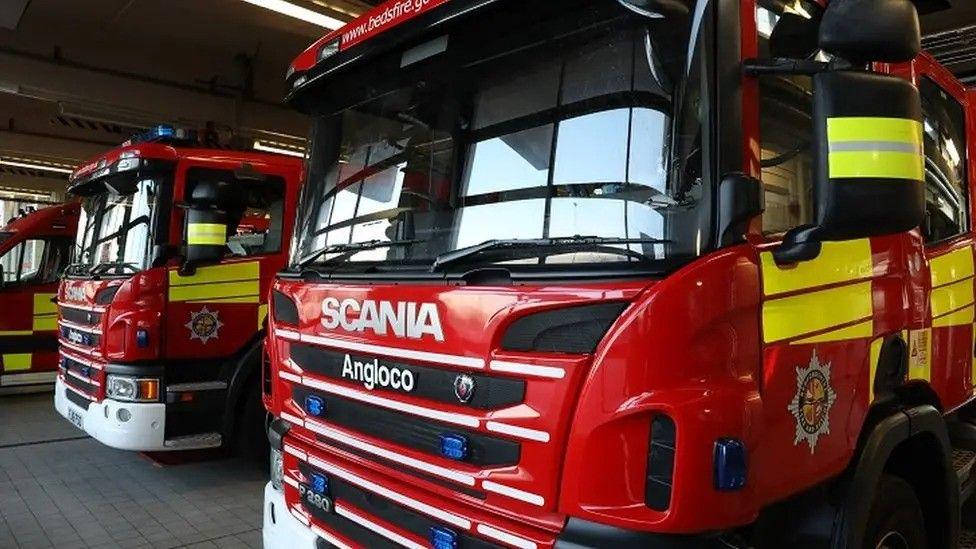 A picture of three fire engines in a fire station building.