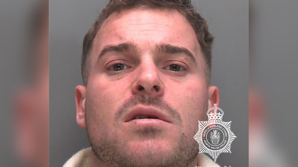 A mugshot of Dean Mears who has brown hair and stubble and is looking directly at the camera with a confused expression.