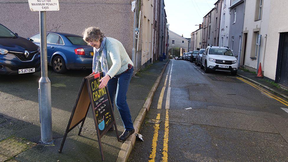 Maggie Hughes yn gosod arwydd