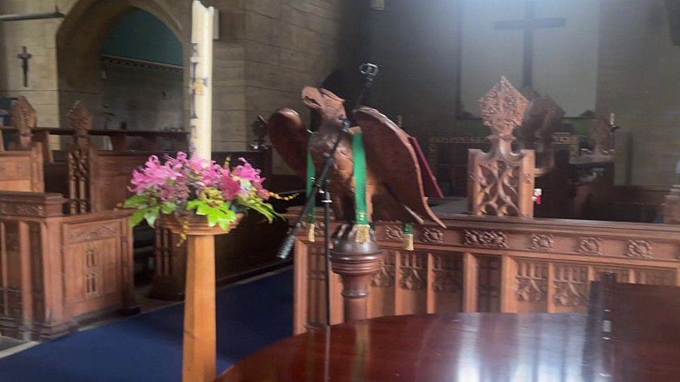 The wooden eagle before the incident. The animal carving is sat on a wooden plinth with green ribbon wrapped around its wings.