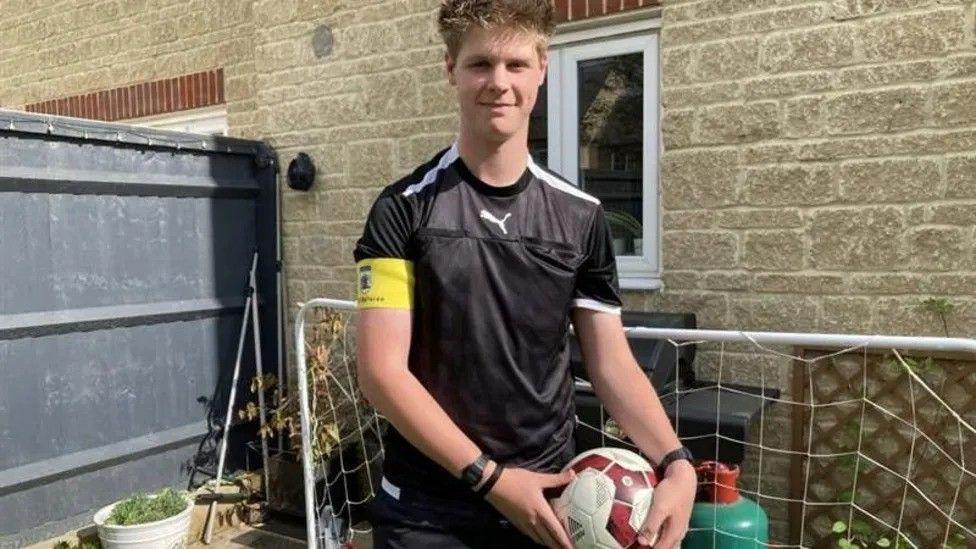 Teenage referee Oscar in his referee uniform and holding a football