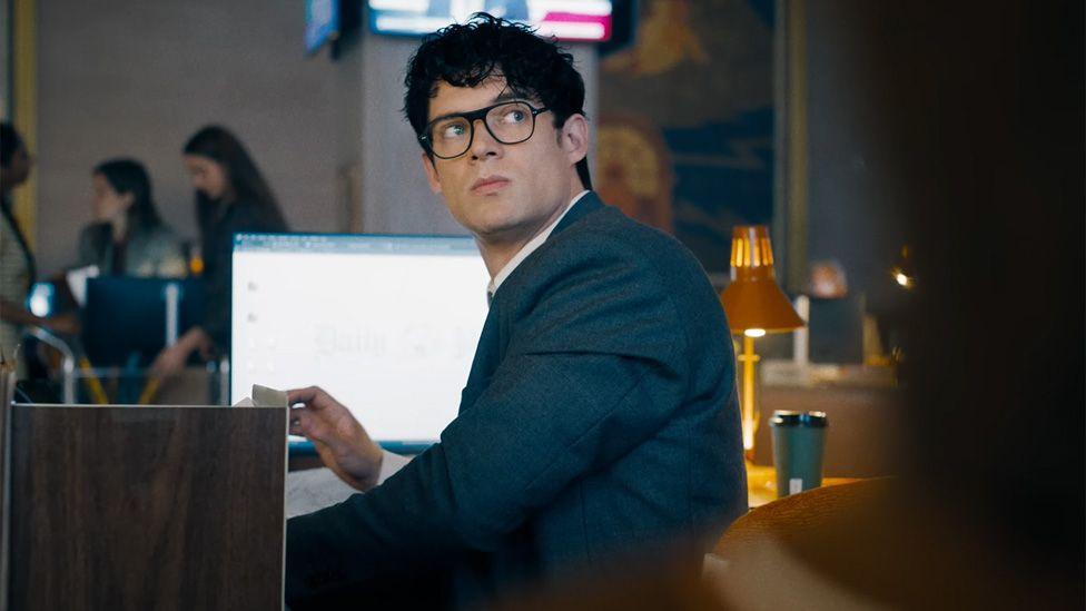 David Corenswet as Clark Kent sitting at a desk in the Daily Planet office in a still from the trailer