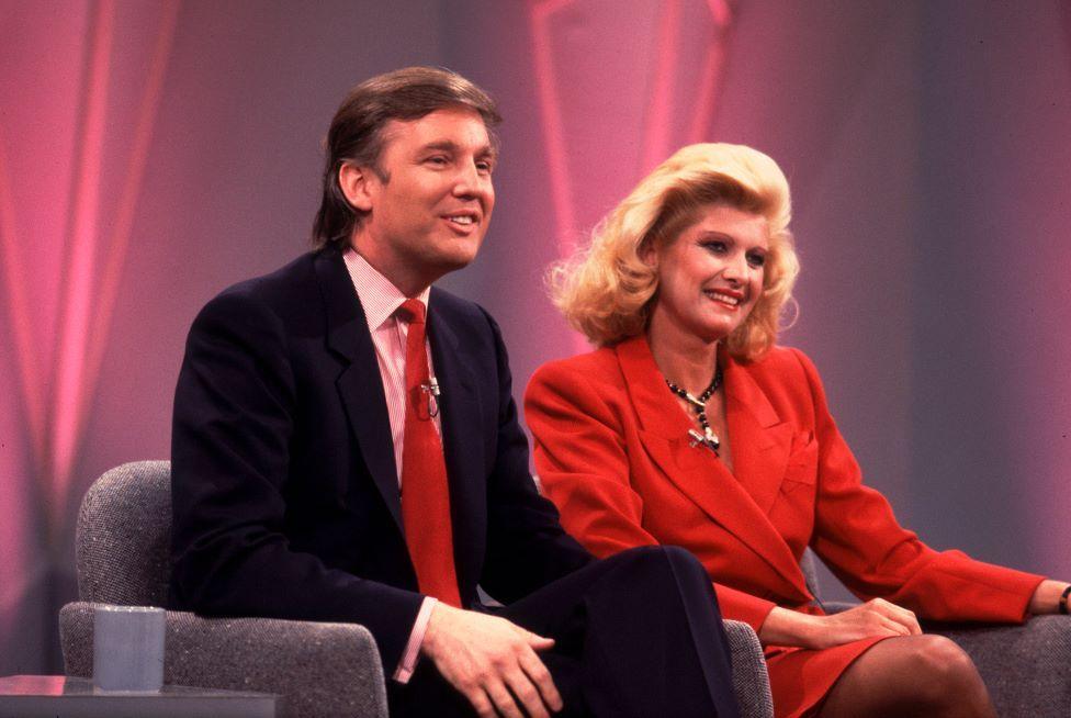 Donald and Ivana Trump sat on chairs on Oprah's set. He is wearing a dark suit and red tie. She is wearing a red suit.