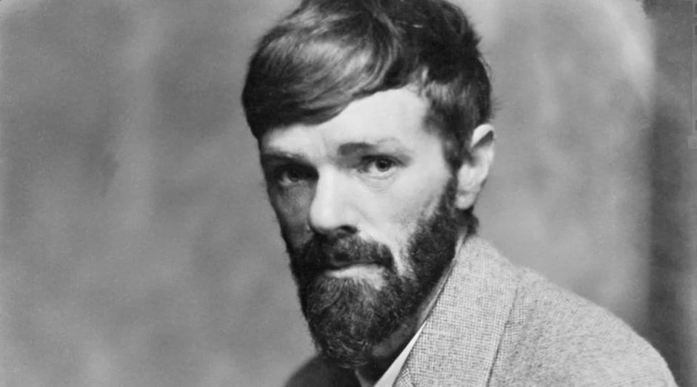 A black and white photograph of a bearded man staring intently at the camera