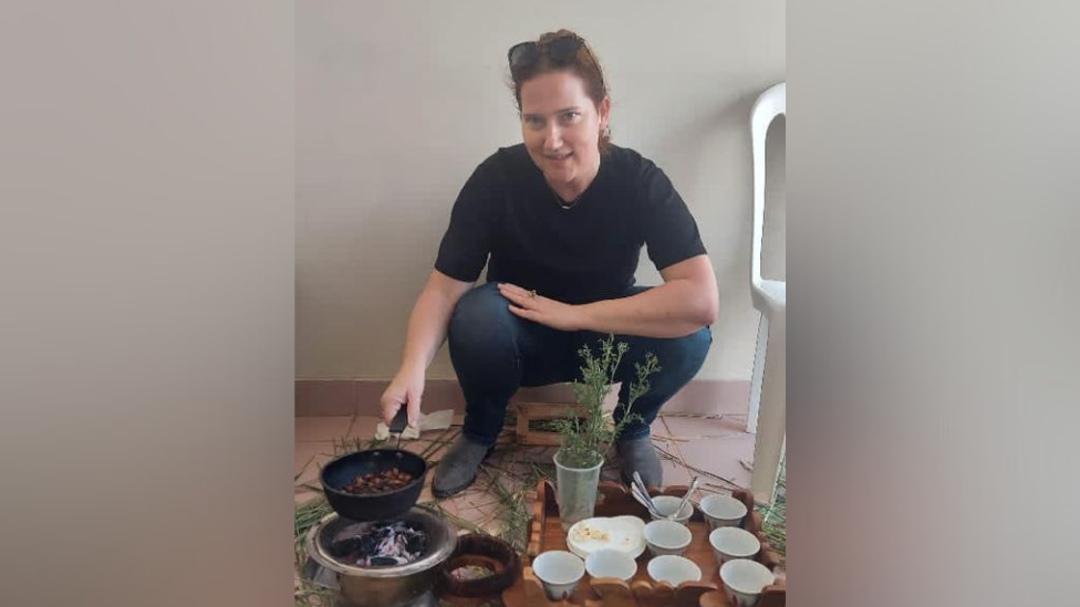 A woman crouched over some bowls and a pan on a stove in a room in Gaza