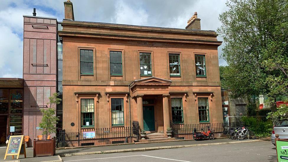 A historic sandstone mansion in Dumfries on a sunny day.