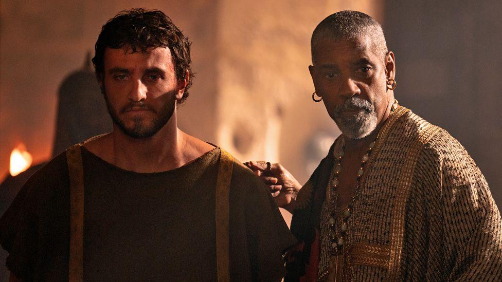 Paul Mescal and Denzel Washington standing together in a scene from Gladiator II