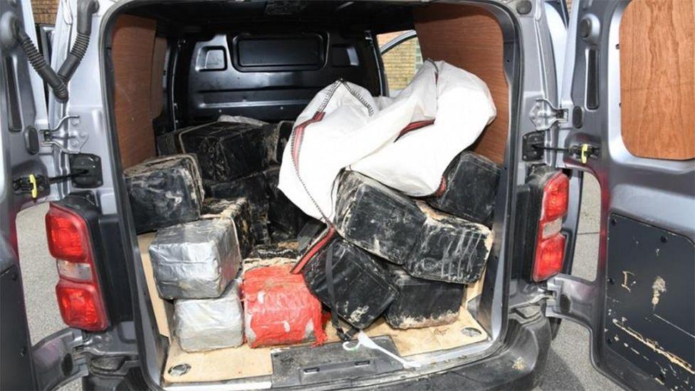 Police photograph of the drugs in large tape blocks piled up in the back of a grey van