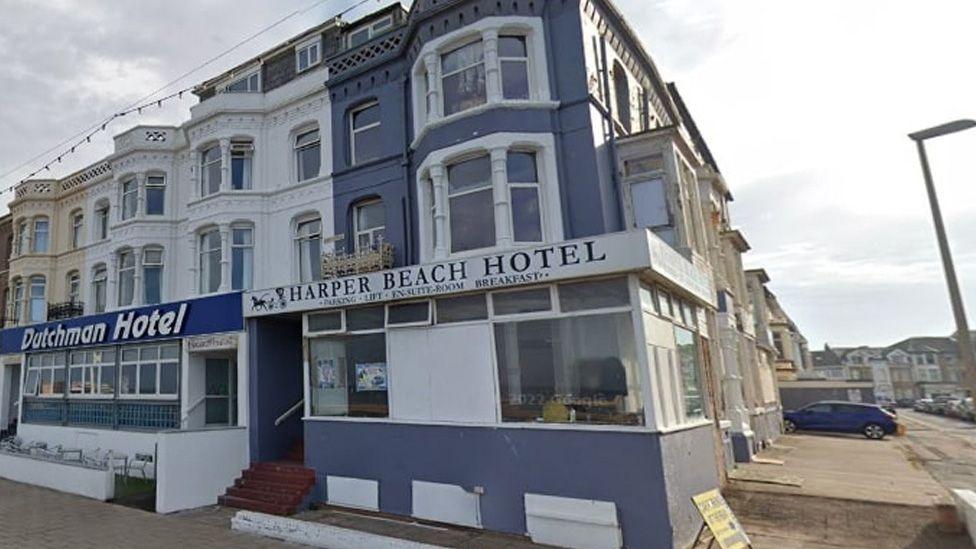 Street view image of the Harper Beach Hotel, a three-storey blue and white building with bay windows situated on a street corner