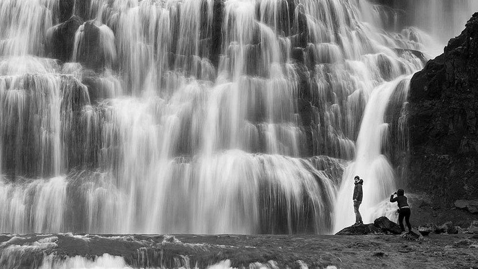 Two figures beside the Dynjandi waterfalls in Iceland