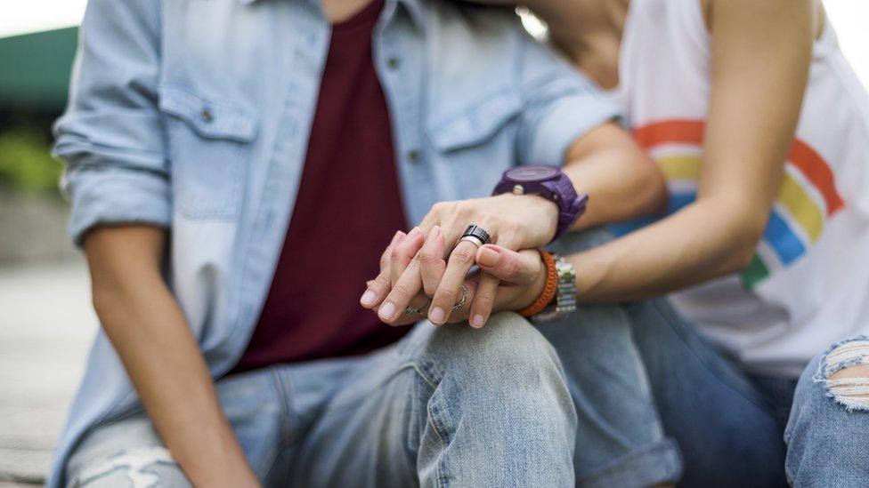 Two unidentified women hold hands