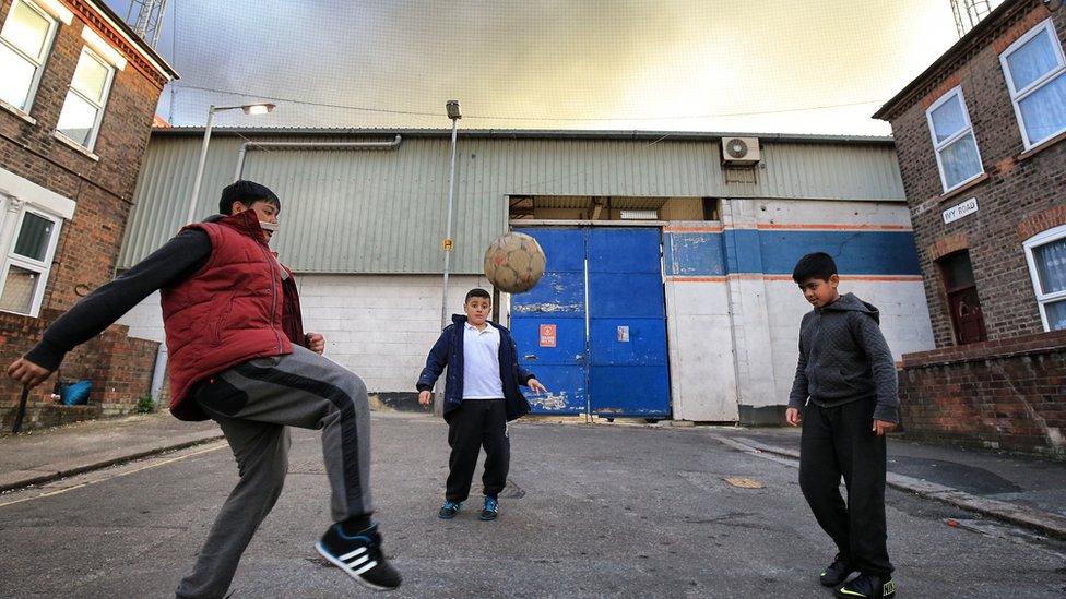 Boys play football in the shadow of Kenilworth Road