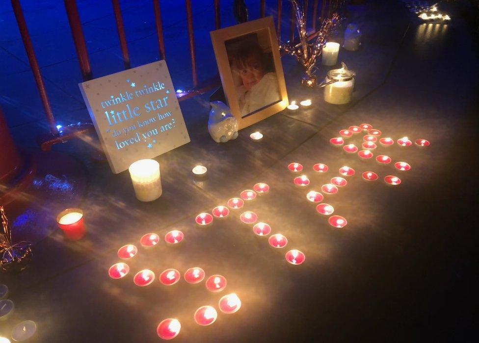 Candles lit in front of a photo of Star Hobson