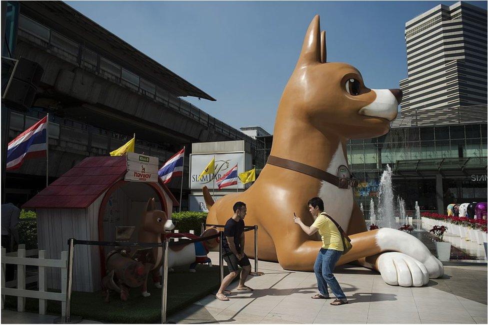 This photo taken on 9 December 2015 shows two men taking pictures with their smartphones next to a 10-metre high sculpture of 'Giant John', one of the characters of the film 'Khun Tongdaeng: The Inspirations', outside a shopping mall in Bangkok.