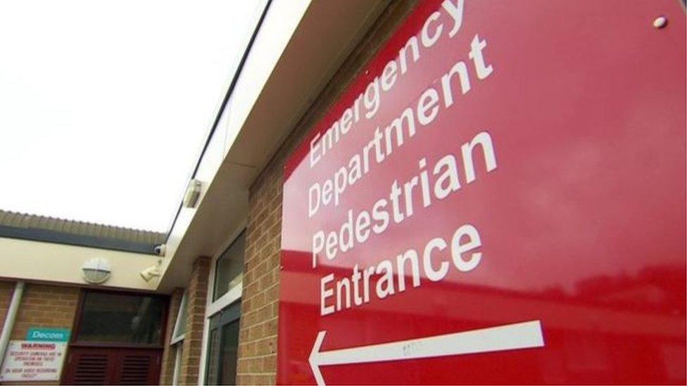 A red sign showing directions to an emergency department in a hospital