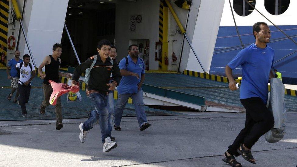 Refugees and migrants run to a bus that will transport them to the metro station, after their arrival in Piraeus from the north-eastern Greek island of Lesbos, 8 September 2015