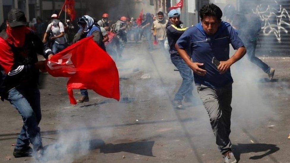 Protesters running and waving red flags