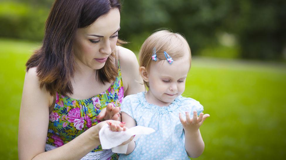 Mother cleans child with wipe