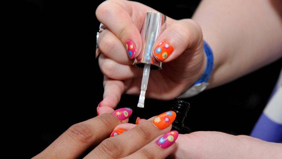 Woman's finger nails being painted with luminous spotted designs