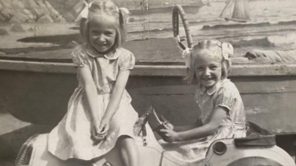 Two girls playing on a toy car