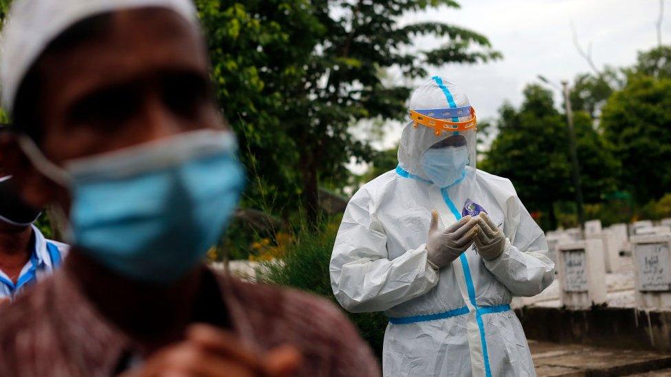 A relative wearing personal protective equipment (PPE) prays before the burial service of a person who died due to the coronavirus disease (COVID-19), at a Muslim cemetery in Yangon, Myanmar on July 16, 2021.