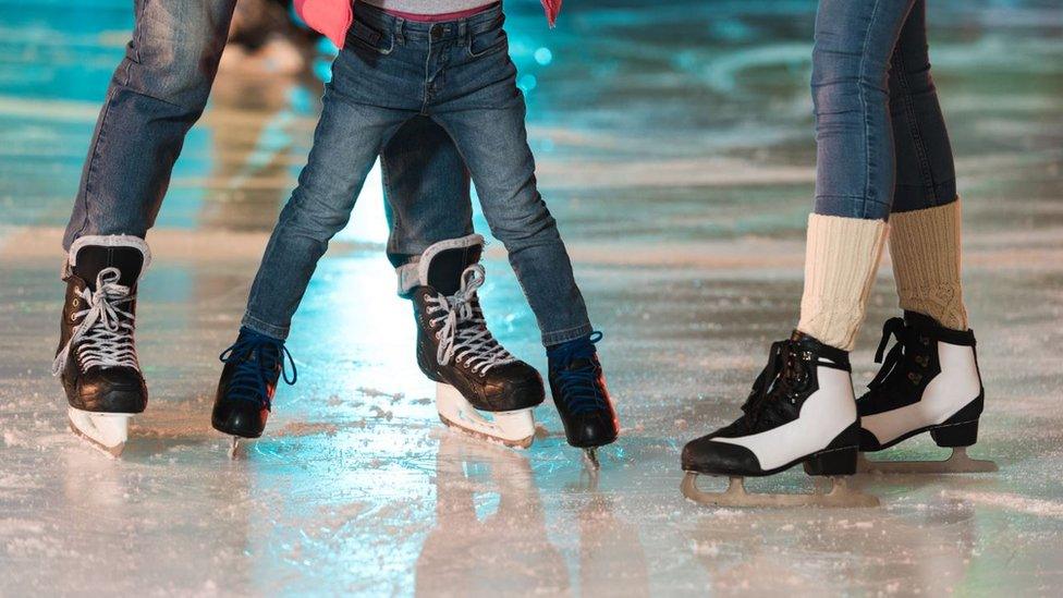 Three people on an ice rink with ice skates