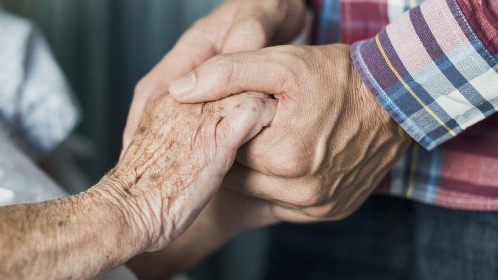 Man holding father's hand in hospital