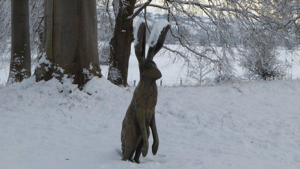 A wooden hare in the snow at Glansevern Hall Gardens, Welshpool