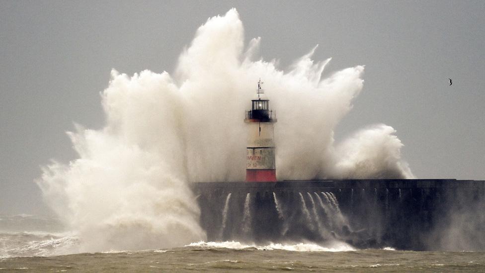 Waves crash over Newhaven Lighthouse and the harbour wall in Newhaven during a storm