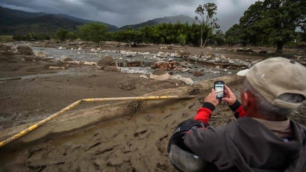 A man takes photos of La Paila river, after a mudslide due to heavy rains affected Corinto in Cauca department, southwest Colombia on November 8, 2017