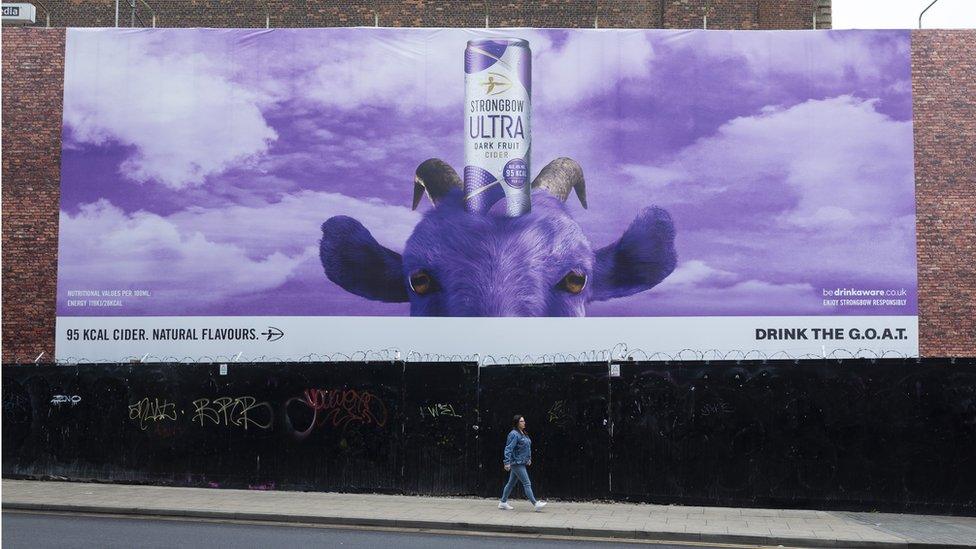 A woman walking past a giant billboard advertisement in Manchester in May of this year