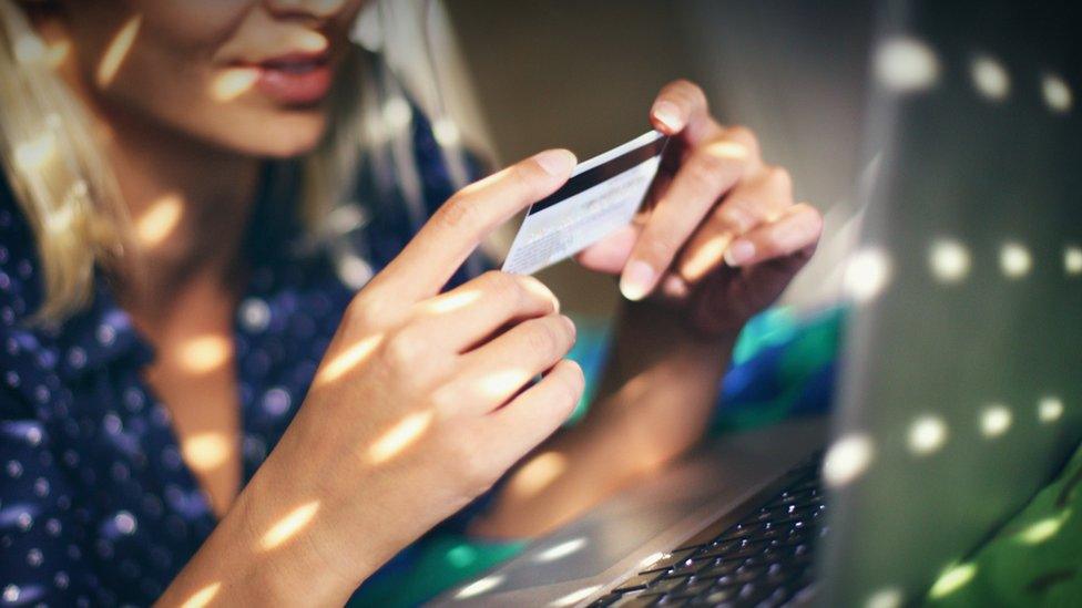 woman holds credit card at computer