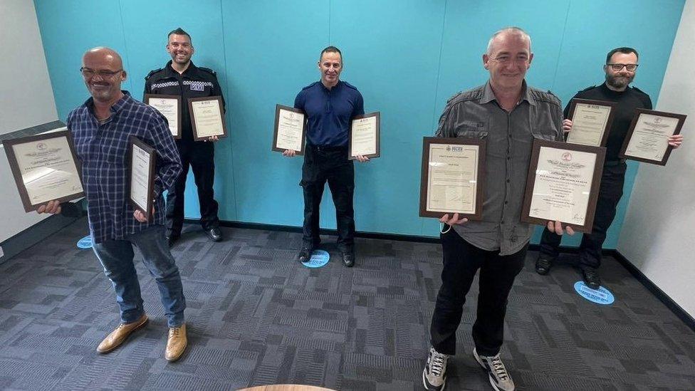 Three police officers and two fishermen hold certificates