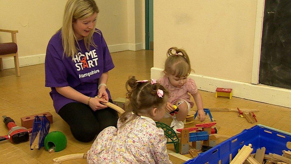 Two girls play with a Home Start volunteer in a purple t-shirt