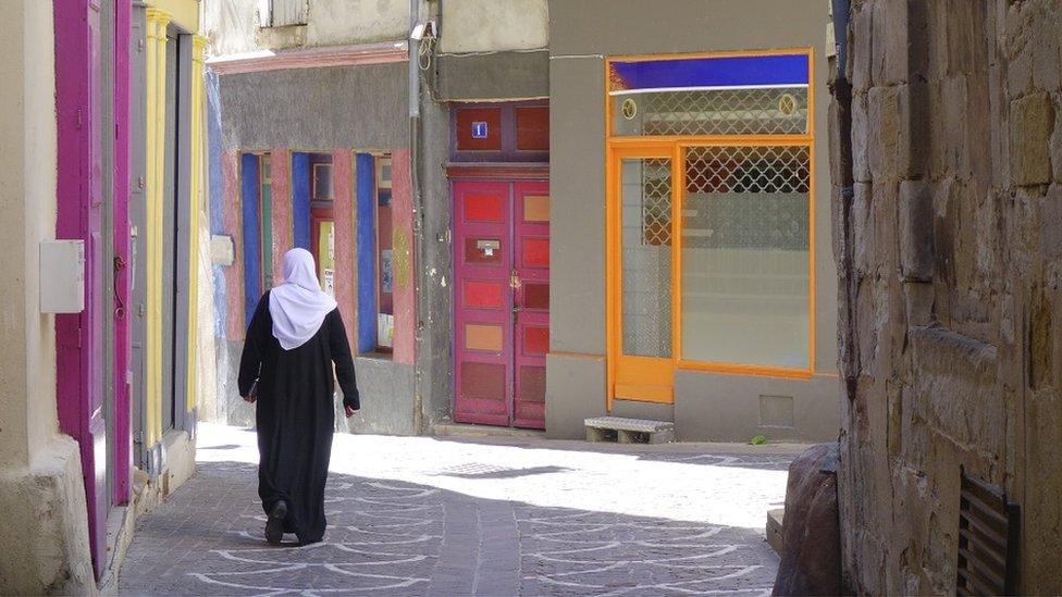 Muslim woman walks down narrow street in town of Lodève is a commune in the Hérault in the South of France