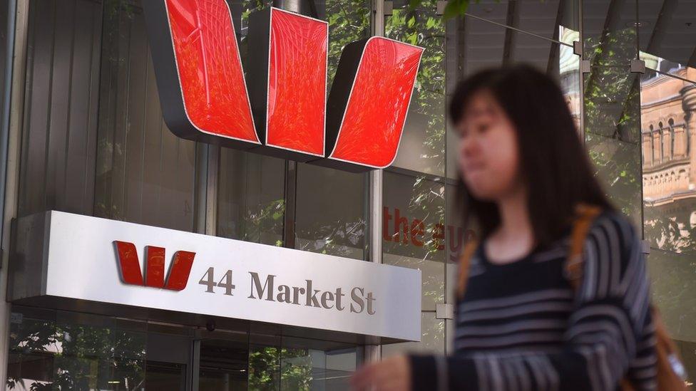 Woman walking past Westpac logo on Market street in Sydney.