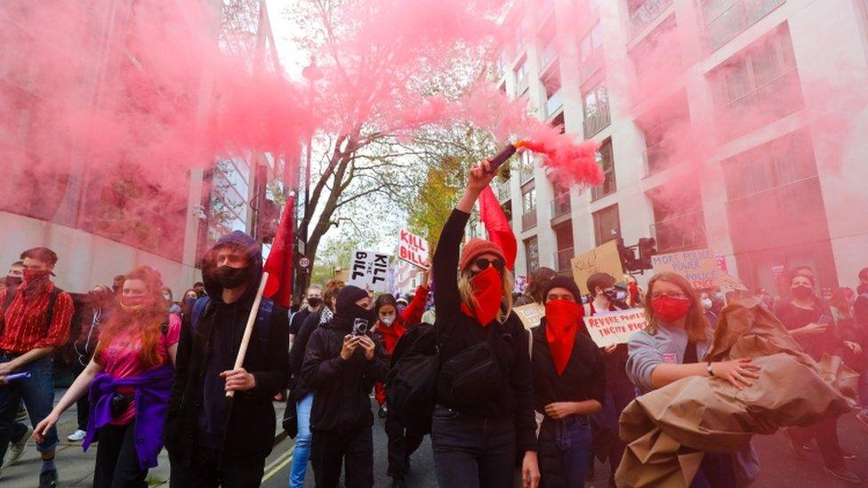 Demonstrators let off flares during a march through central London